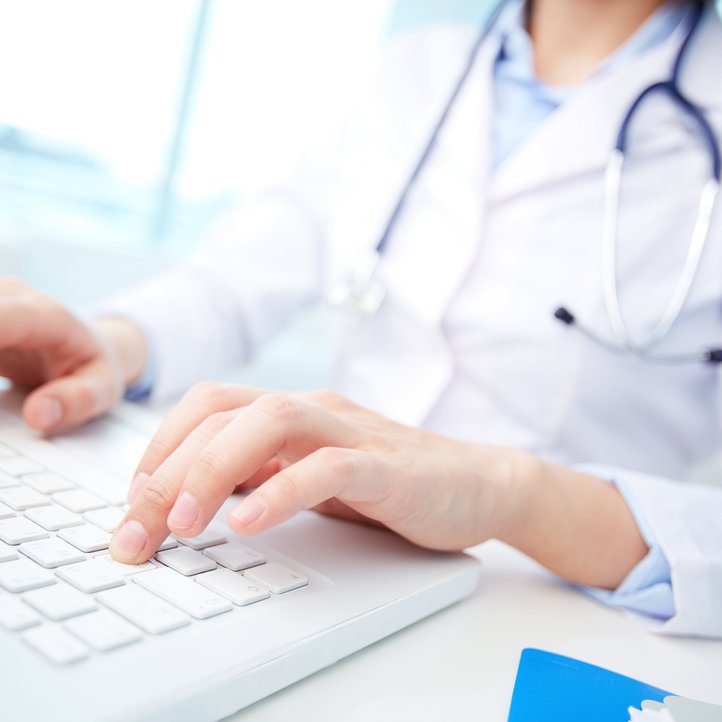 Arzt mit einem weißen Kittel und einem Stethoskop tippt auf einer weißen Tastatur