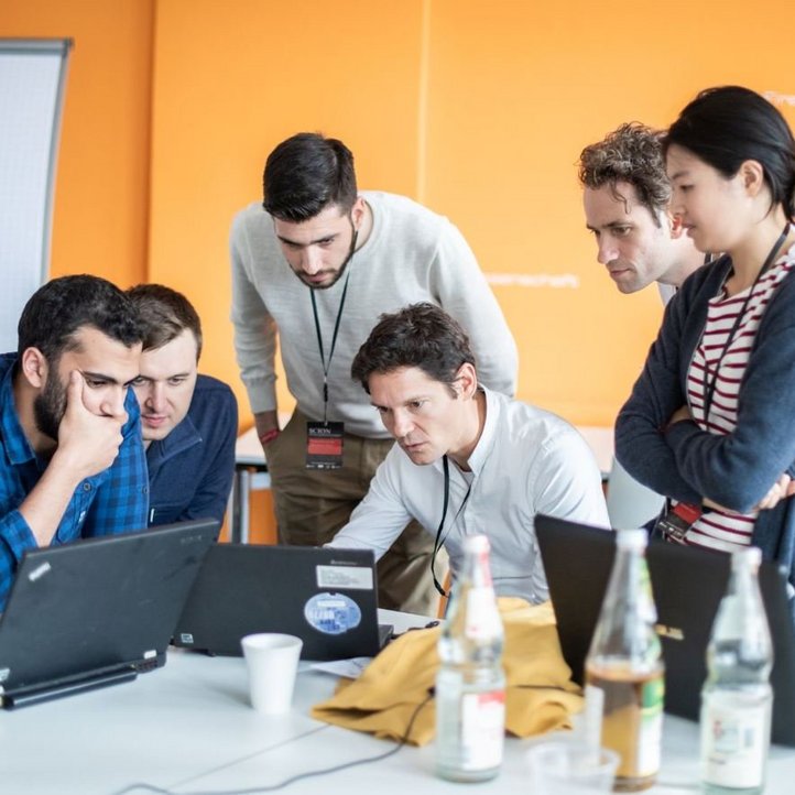 vier Menschen sitzen vor Laptops 