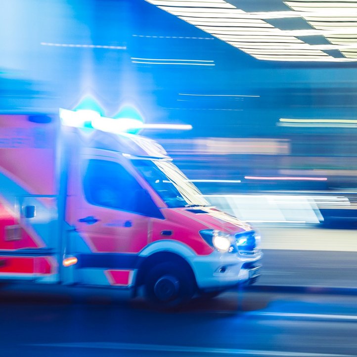 Ein Krankenwagen mit Blaulicht fährt zu einer Notrufzentrale 